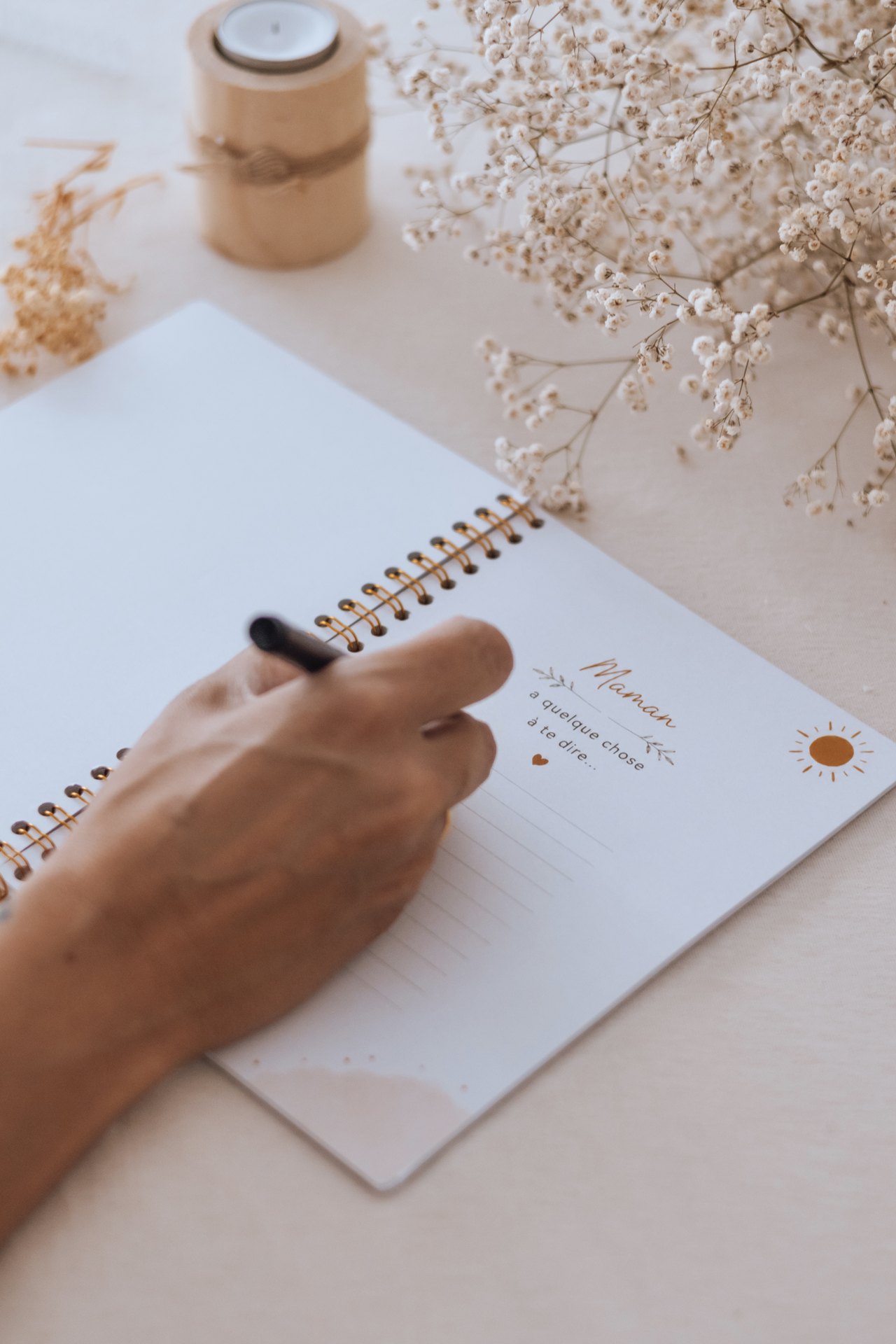 Future maman écrivant les premiers mots de la page « Maman » de son carnet de grossesse — Entre Deux