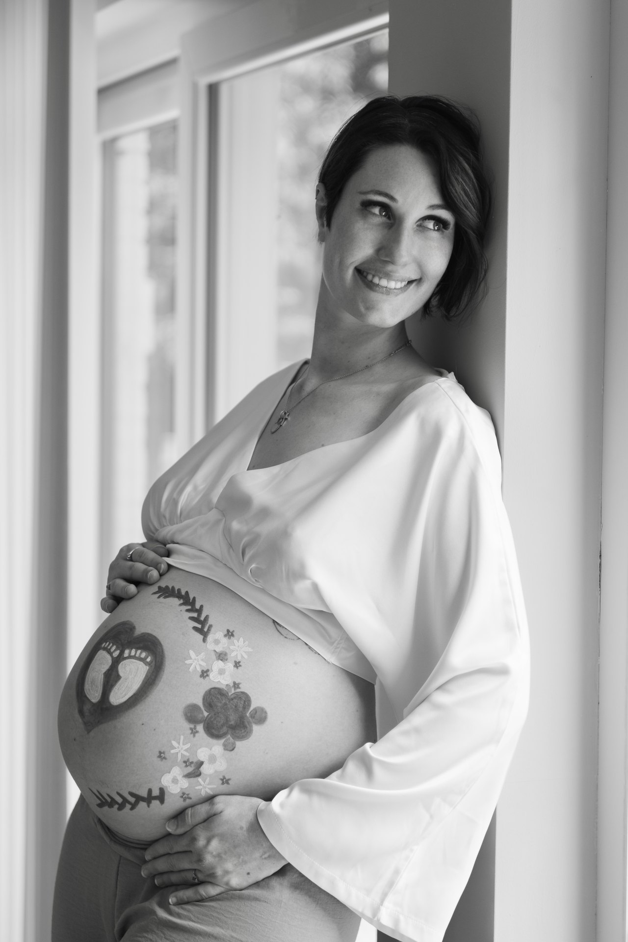 Portrait noir et blanc d'une future maman au ventre peint