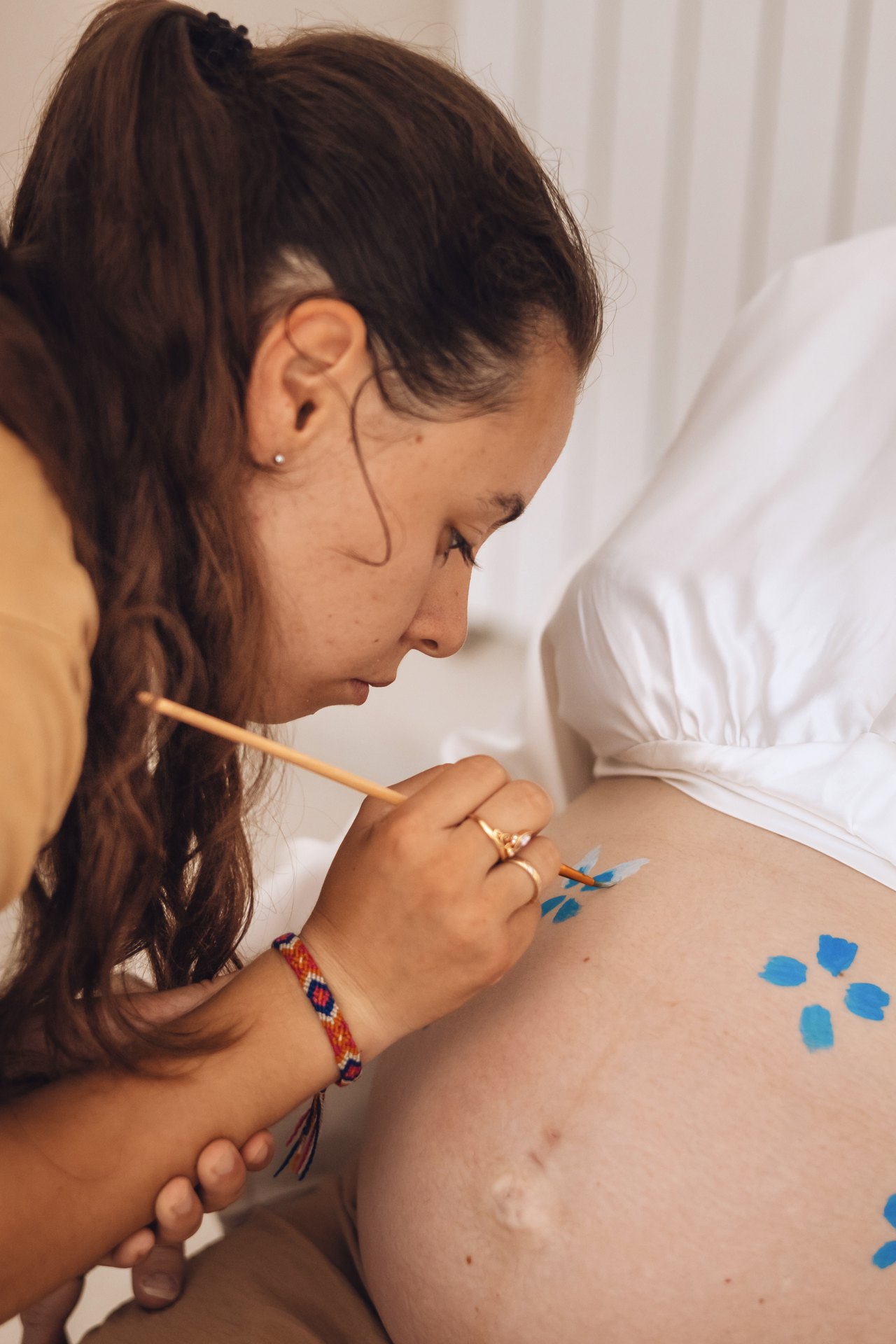 La grimeuse peint délicatement le ventre d'une future maman