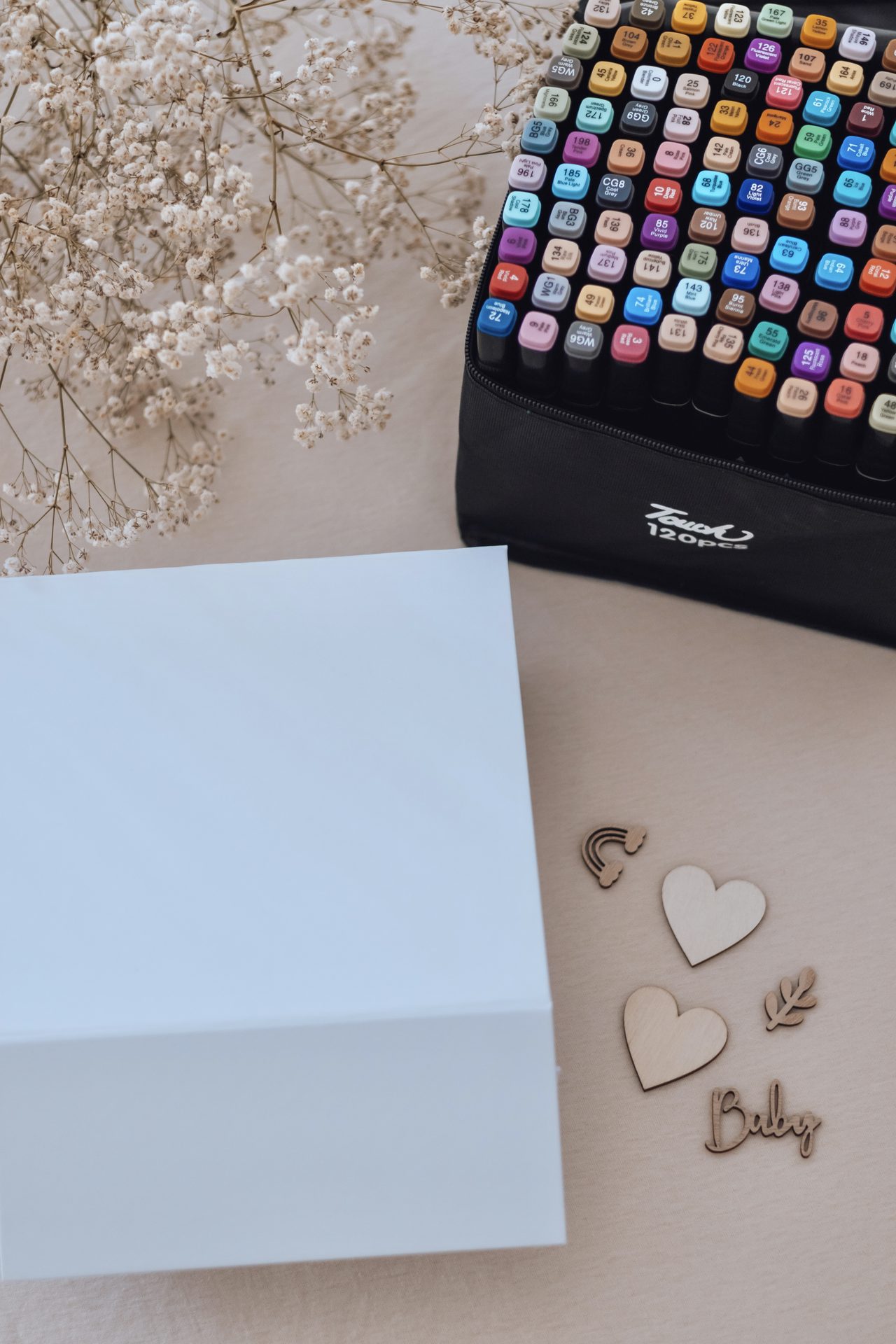 Le coffret encore blanc, les cœurs de bois et le prénom à coller, devant la palette de feutres — Entre Deux