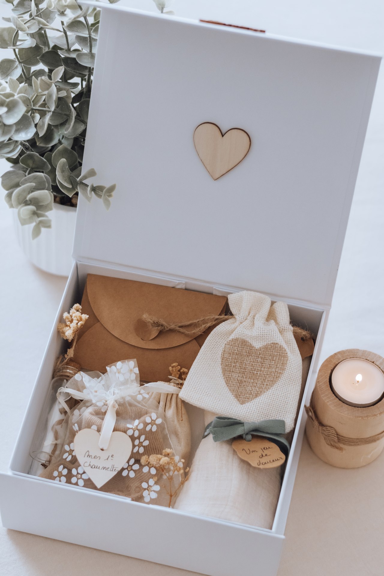 Le coffret ouvert et garni : pochettes, cœur en dentelle et fiole, avec une bougie à côté — Entre Deux