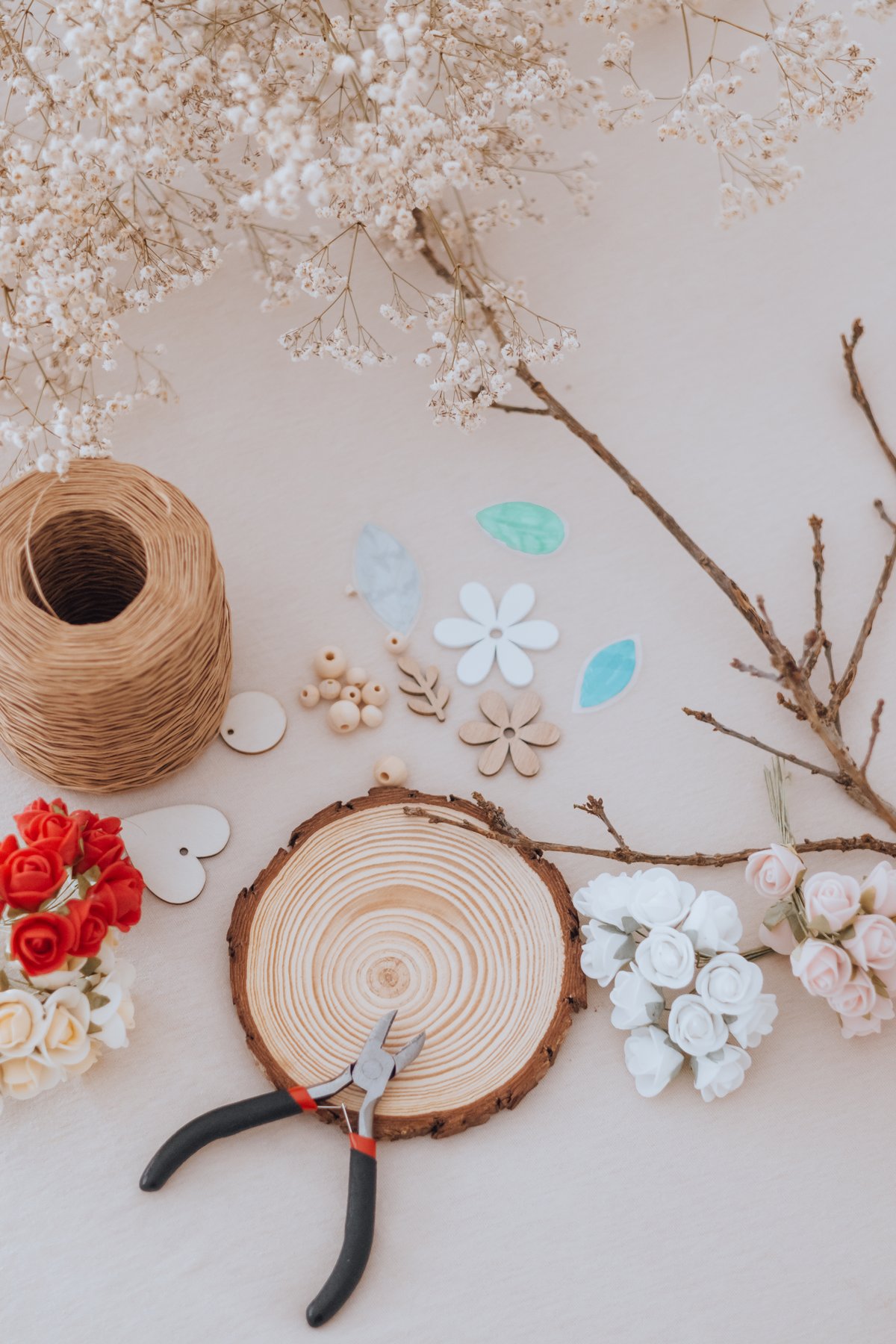 Matériel de l'arbre des valeurs : perles, fleurs, ficelle et pinces sur un rondin — Entre Deux