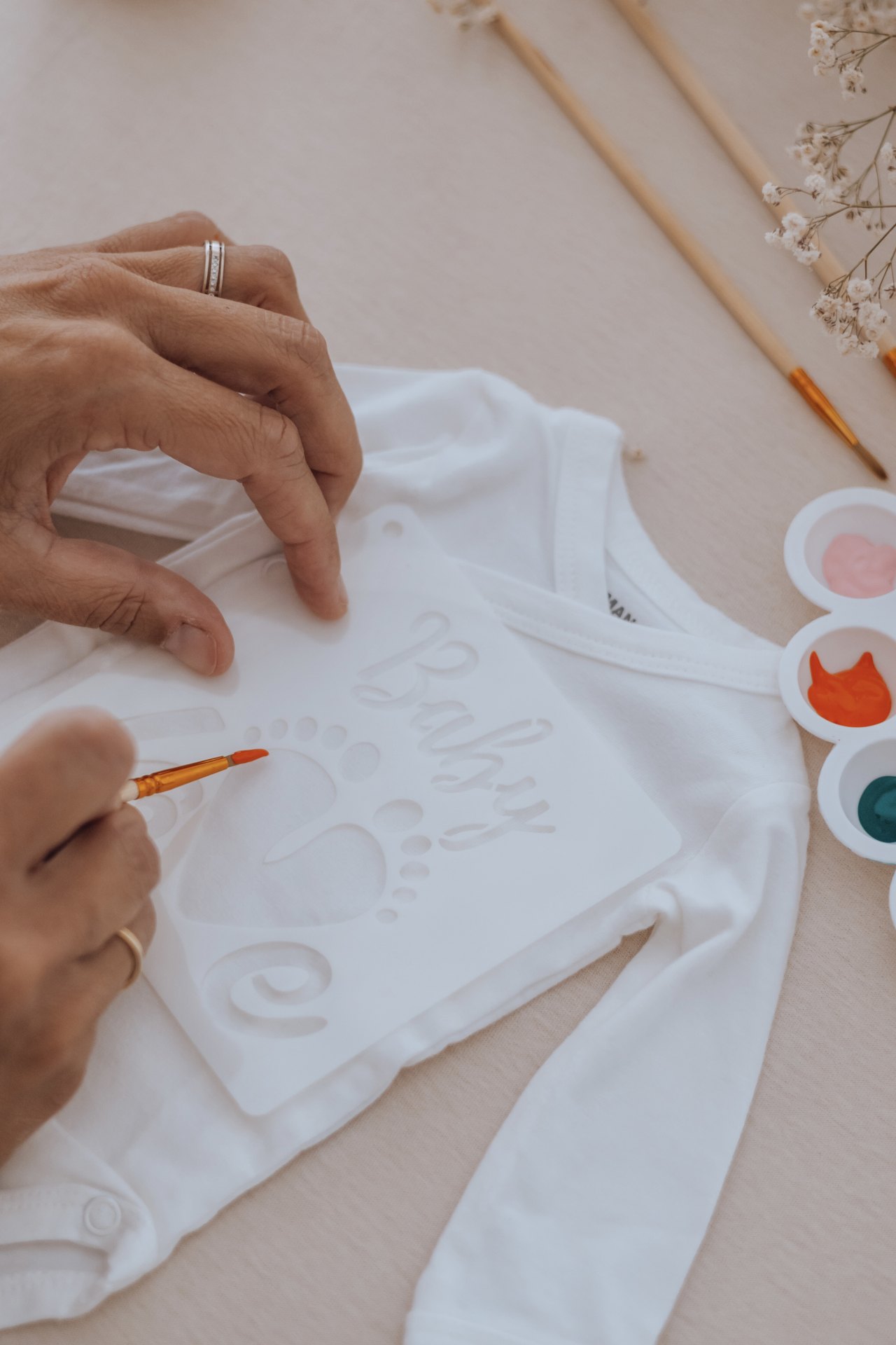 Motif « Baby love » peint au pochoir sur un vêtement, pinceau à la main