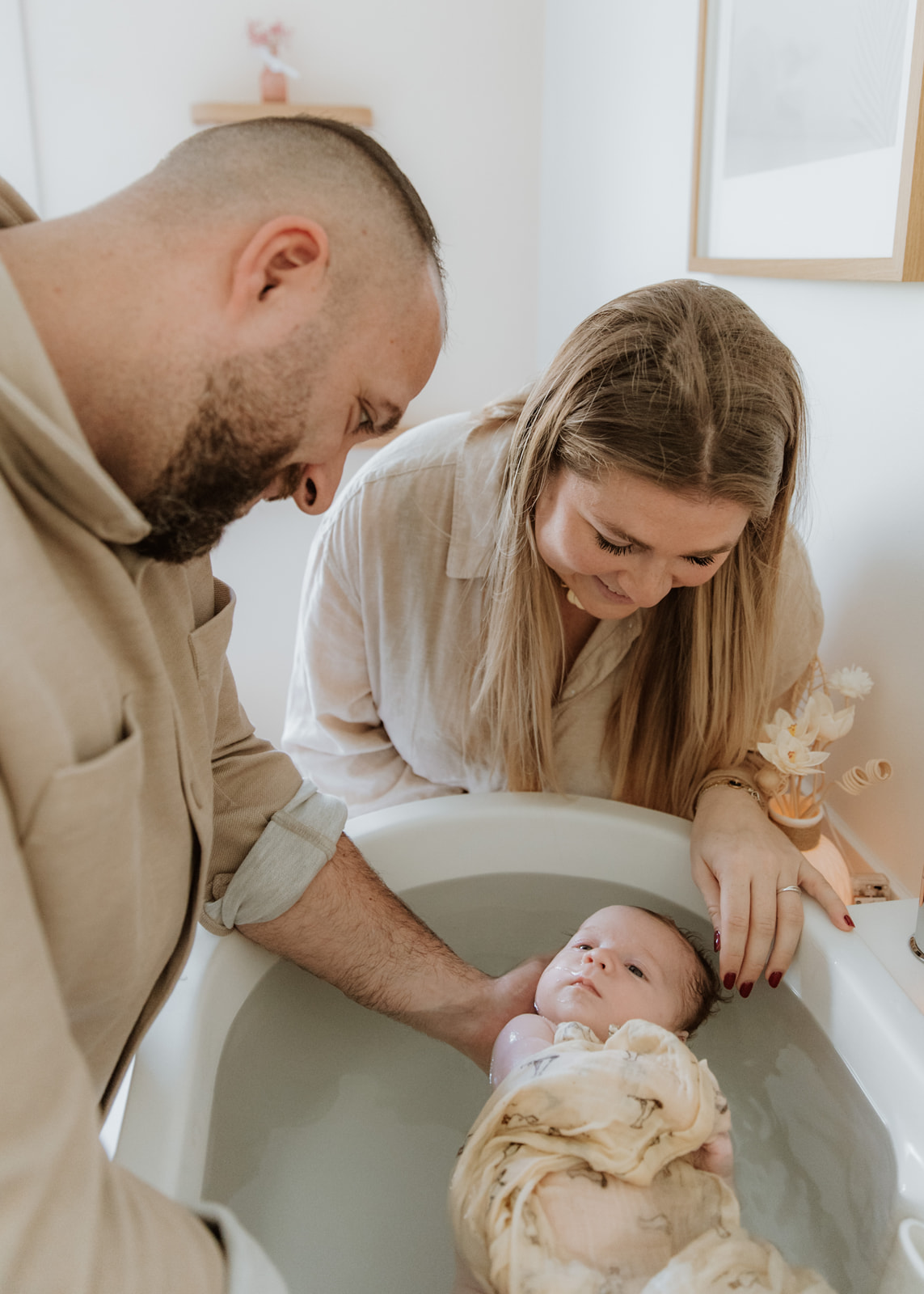Parents souriants autour du bain enveloppant de leur bébé — Entre Deux
